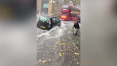 ロンドンの洪水: Man brushes away water as heavy rain hits King’s Cross