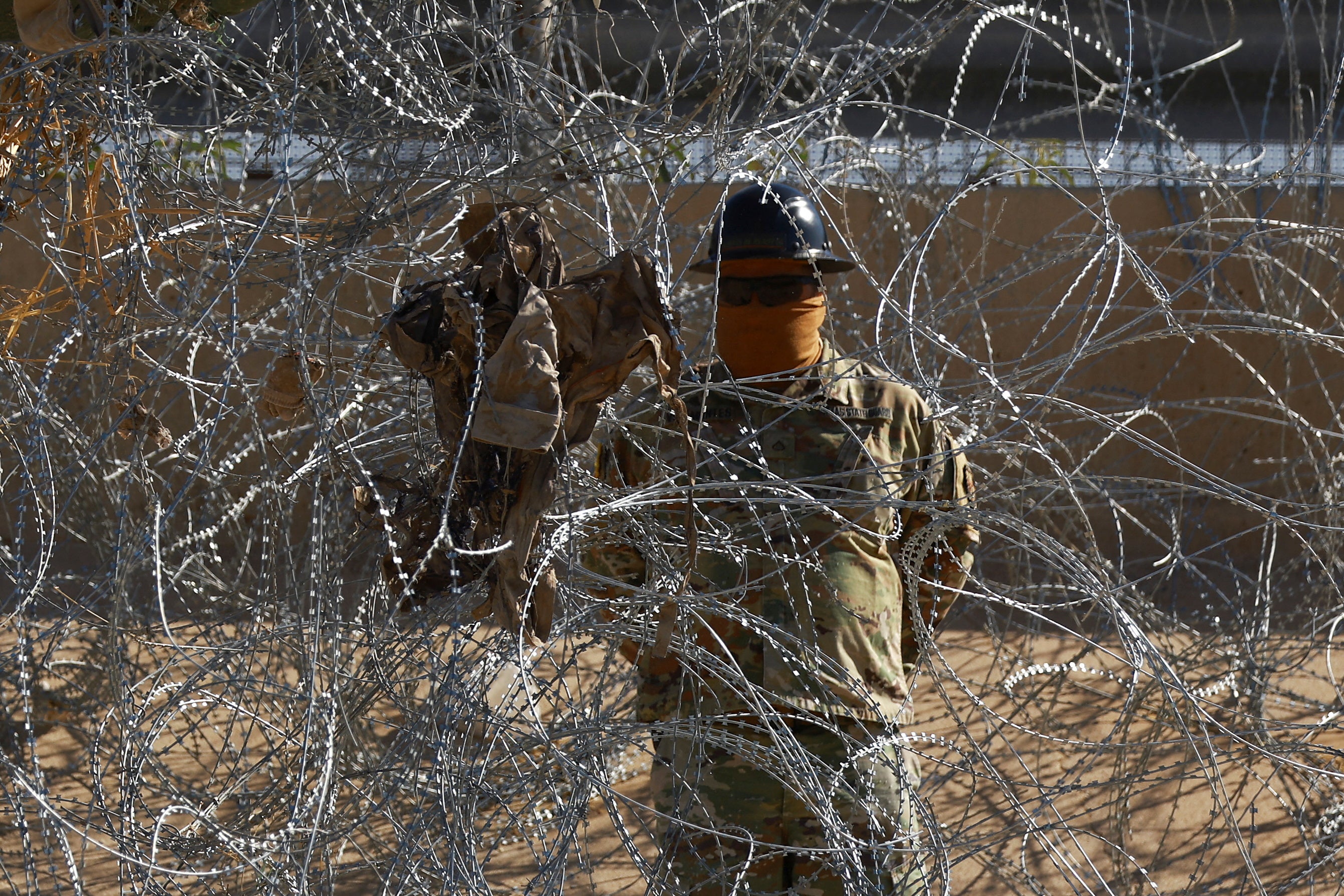 A member of the U.S. military stands behind wire at the U.S.-Mexico border, where Trump has surged thousands of service members to detain and search migrants