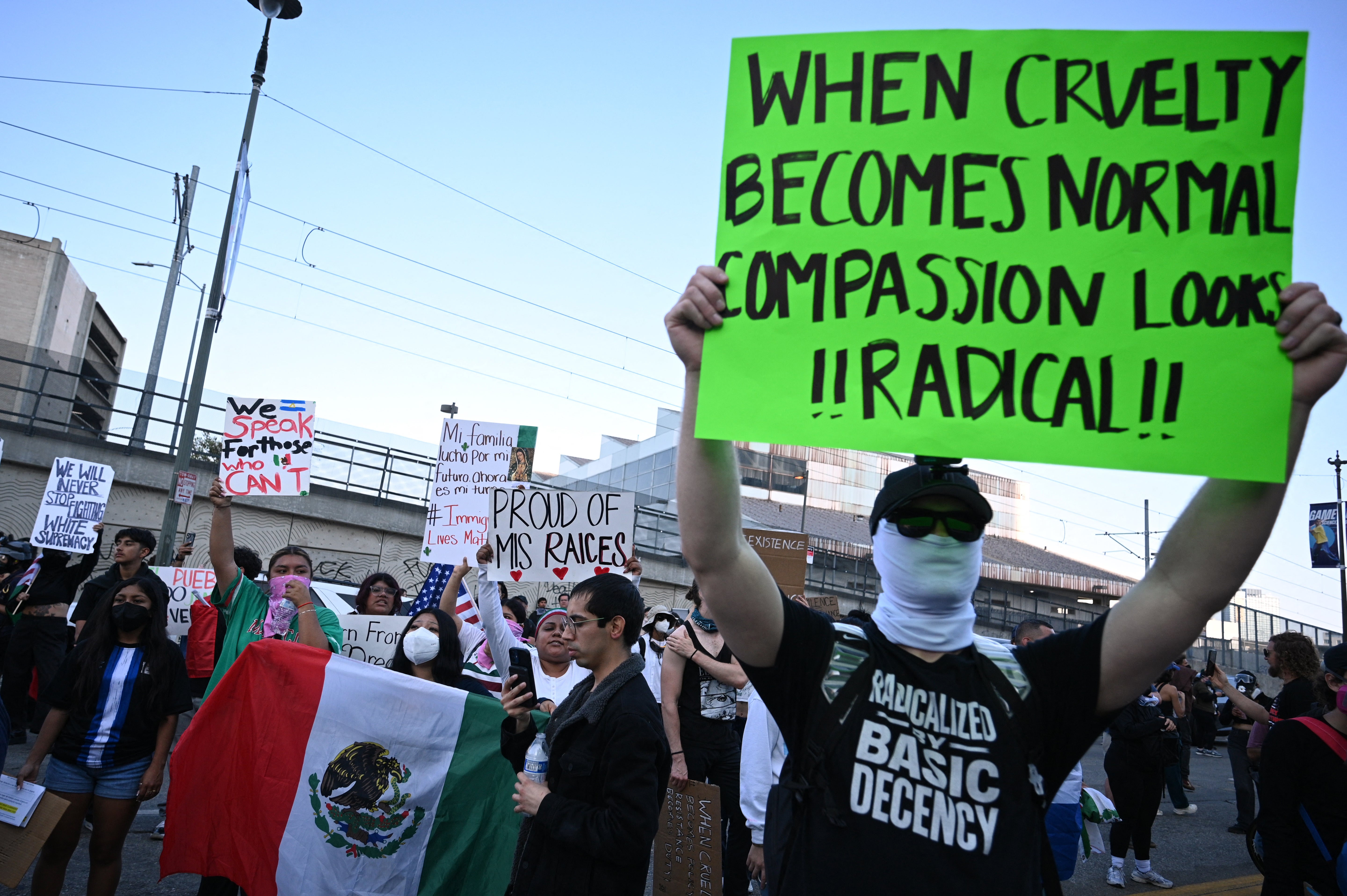 Anti-ICE protesters hold up signs and the Mexican flag in Los Angeles on Thursday