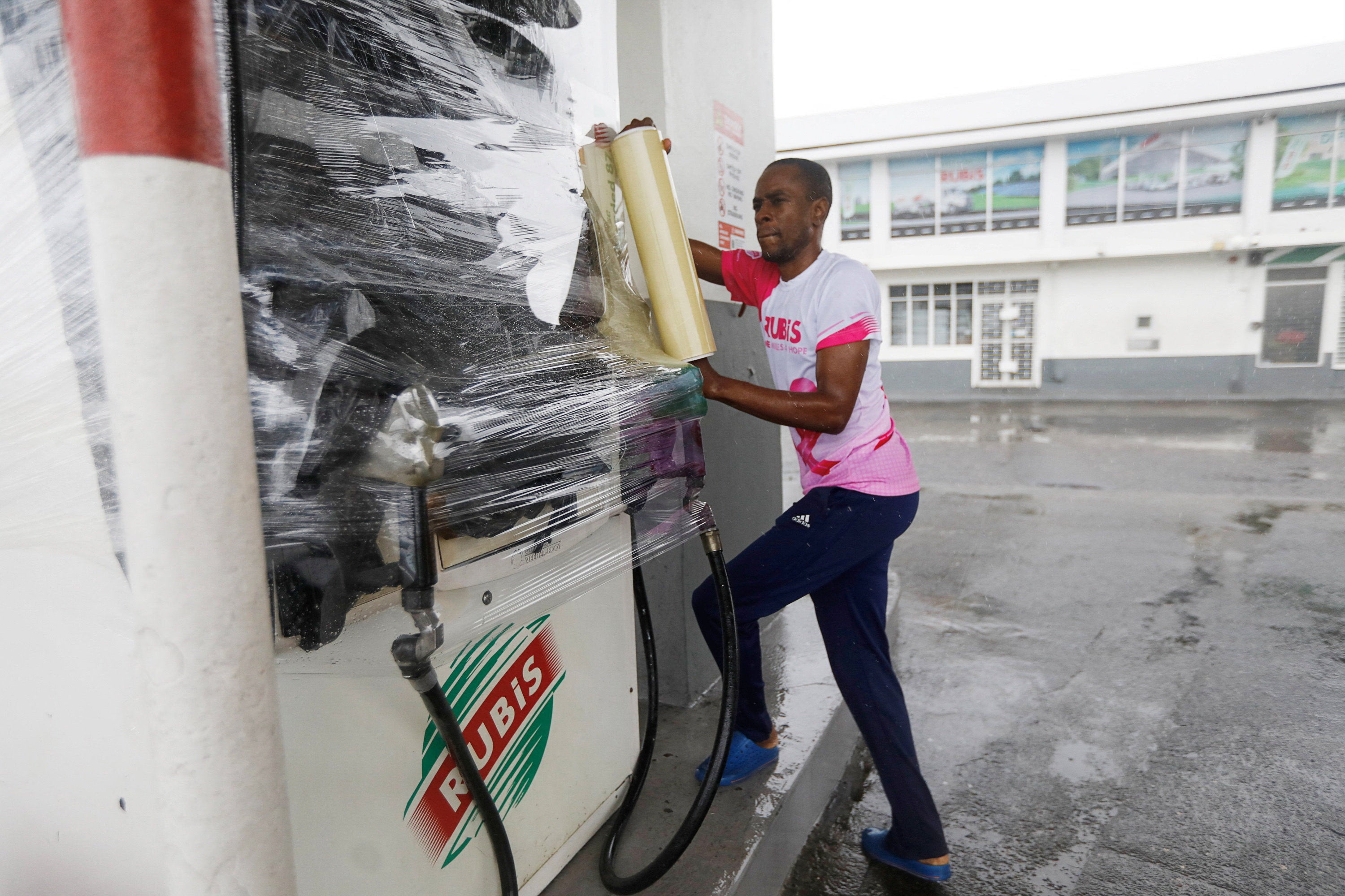 A gas station worker in Kingston wraps a gas pump on Monday
