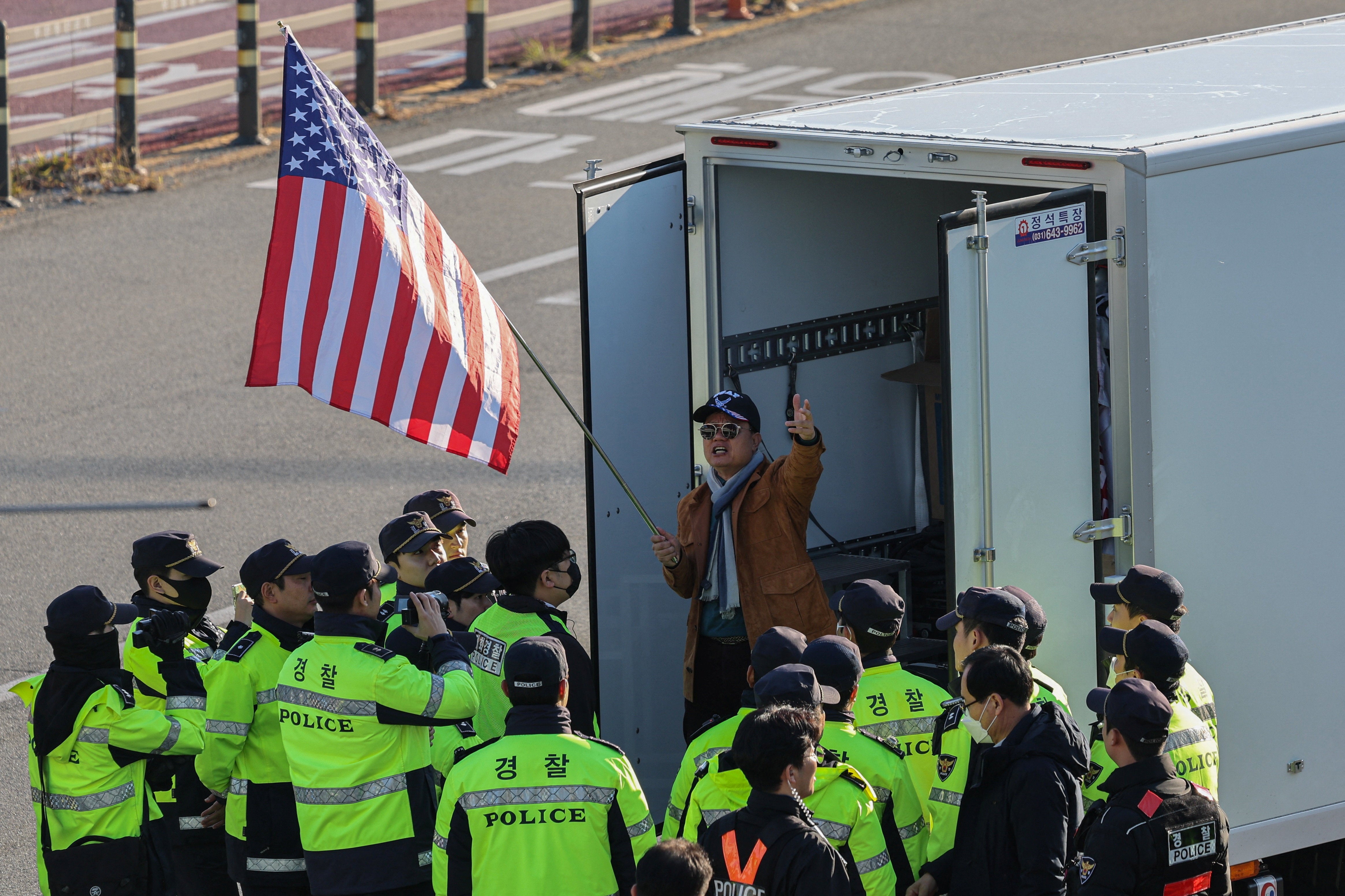 South Korean police surround an anti-China protester holding a U.S. flag