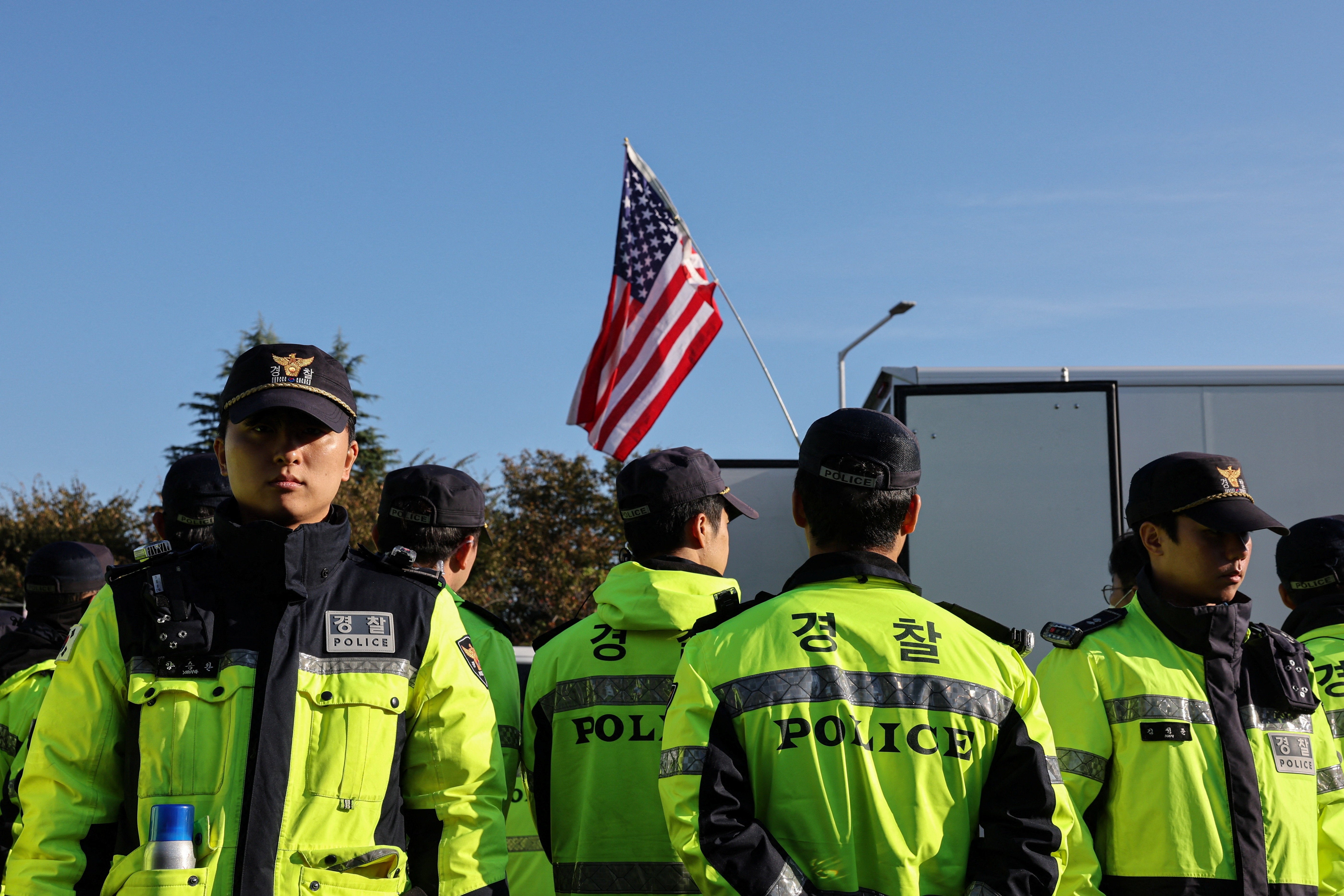 Police stand guard as anti-China protesters demonstrate near Gimhae International Airport in Busan, South Korea