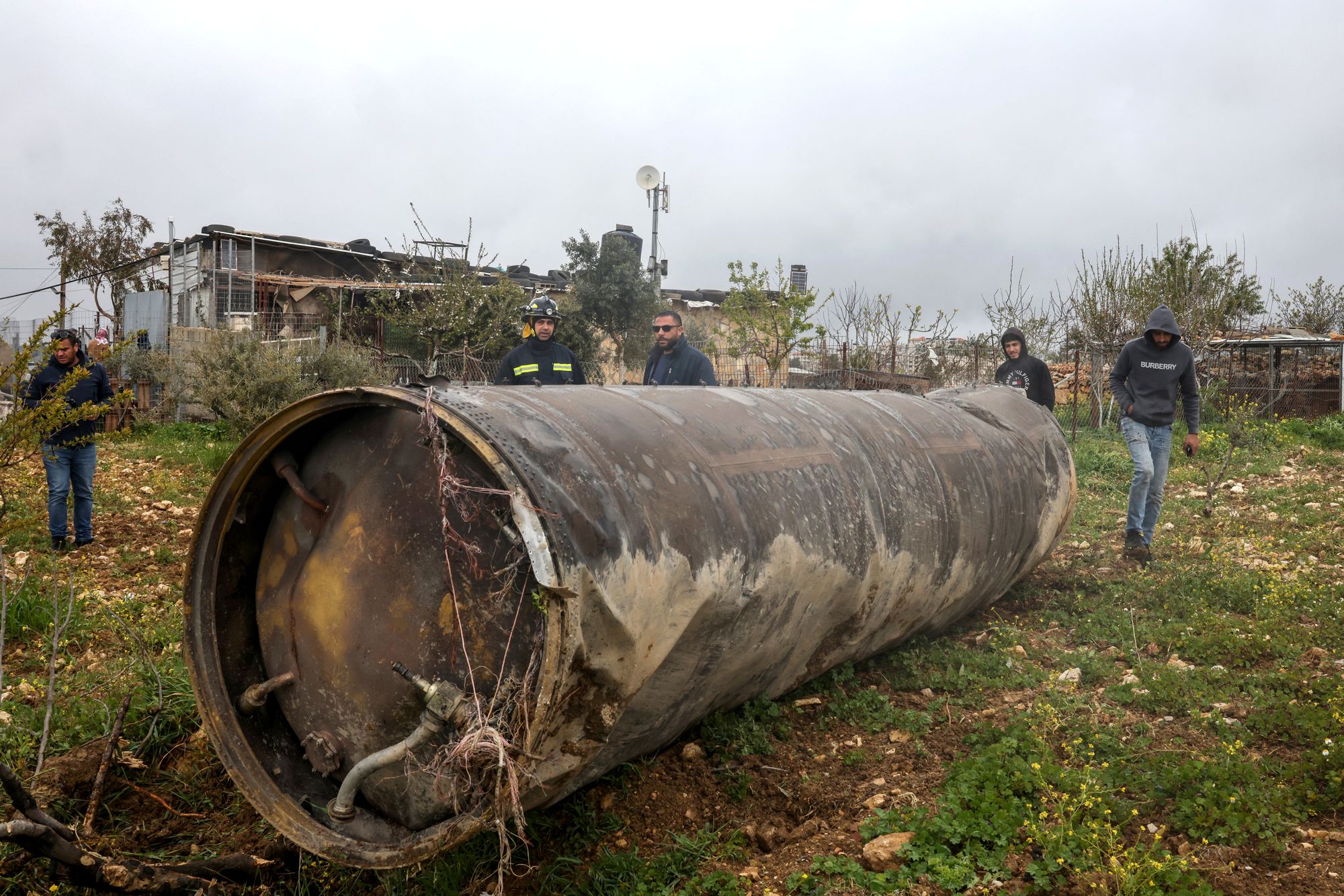 Palestinian residents inspect the remnants of an missile that landed in the Israeli-occupied West Bank village of Beitin, northeast of the city of Ramallah