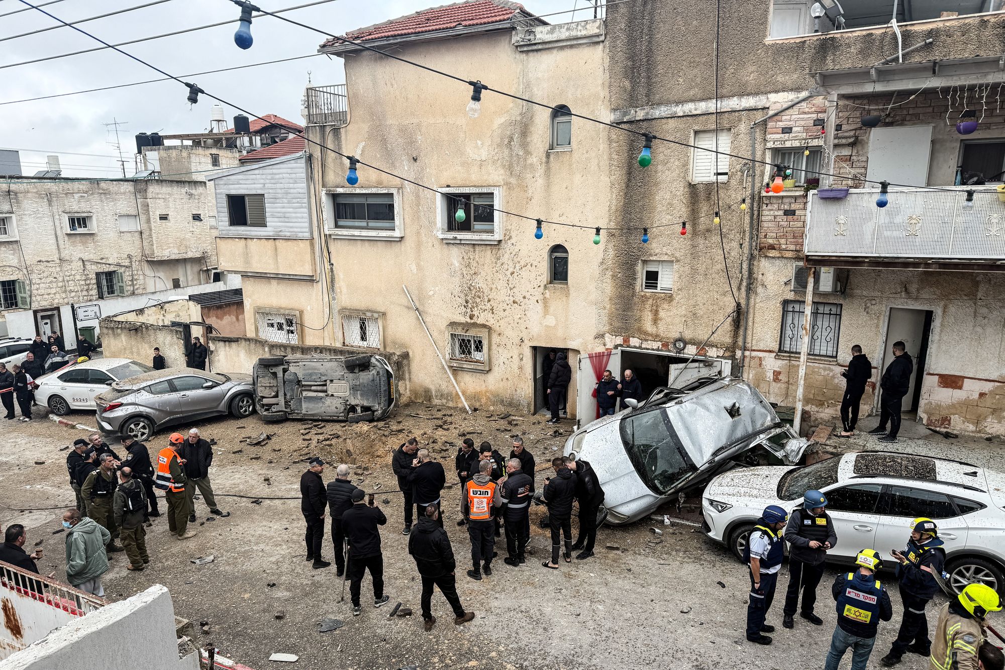 Members of the Israeli emergency services, security officials and onlookers gather at the missile impact site, after Iranian missile barrages