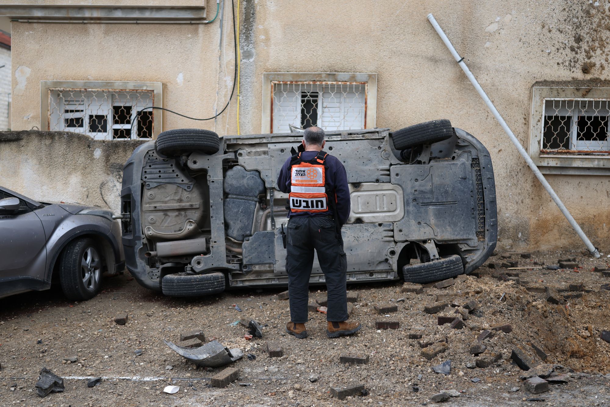 A man surveys the damage to a car following a projectile strike in the Arab-Israeli city of Kfar Qassem