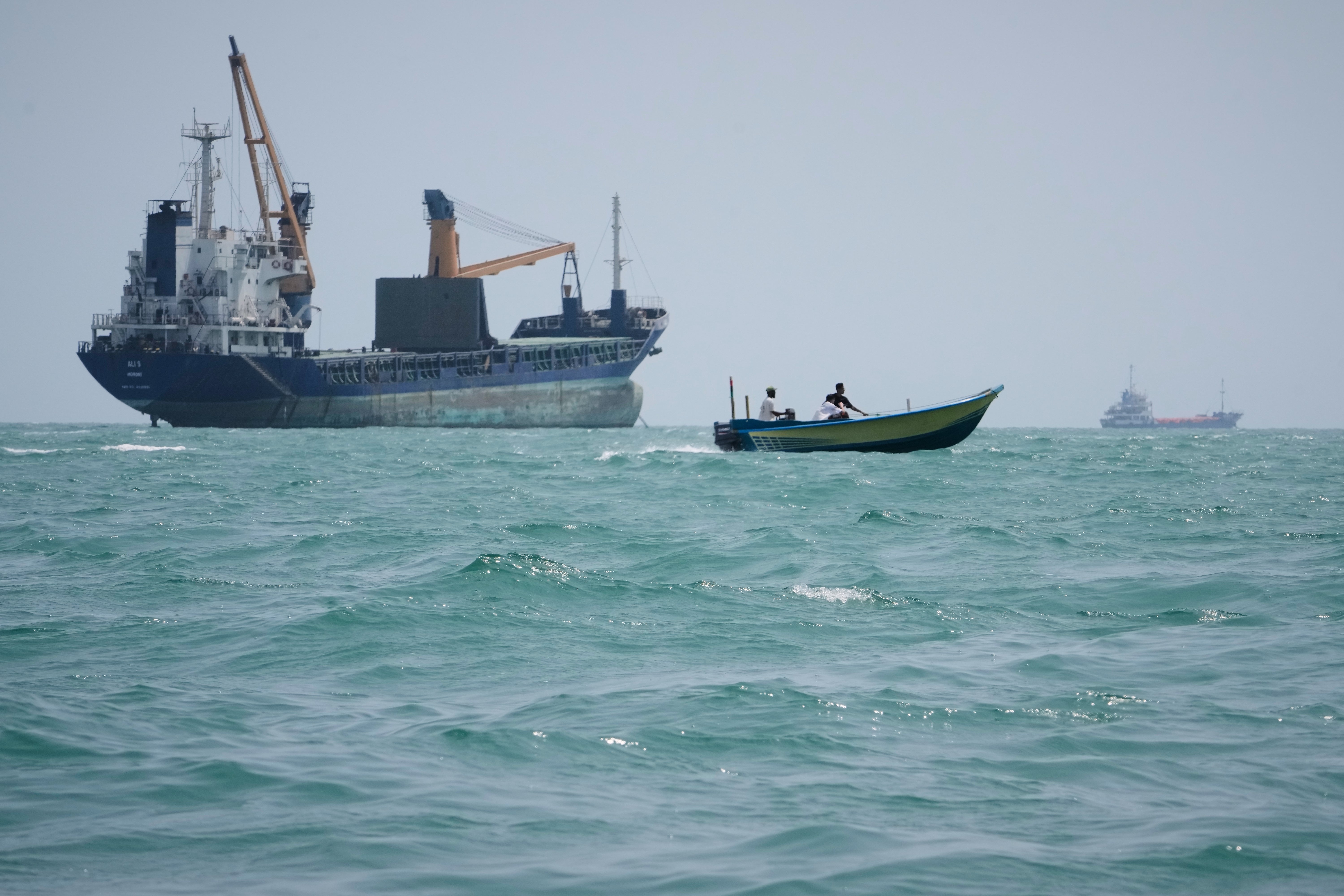 A motorboat passes a general cargo ship anchored in the Strait of Hormuz off Bandar Abbas, Iran