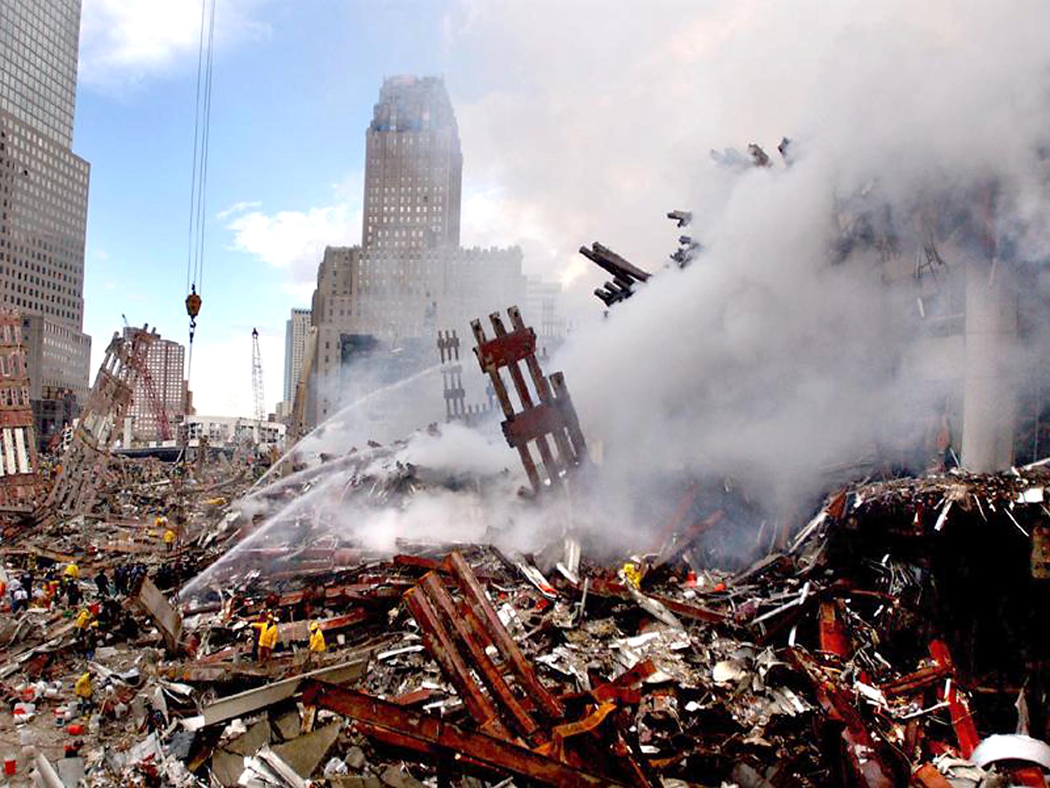 Fires still burn amidst the rubble as firefighters and other emergency response personnel make their way over the debris left in the wake of the attacks