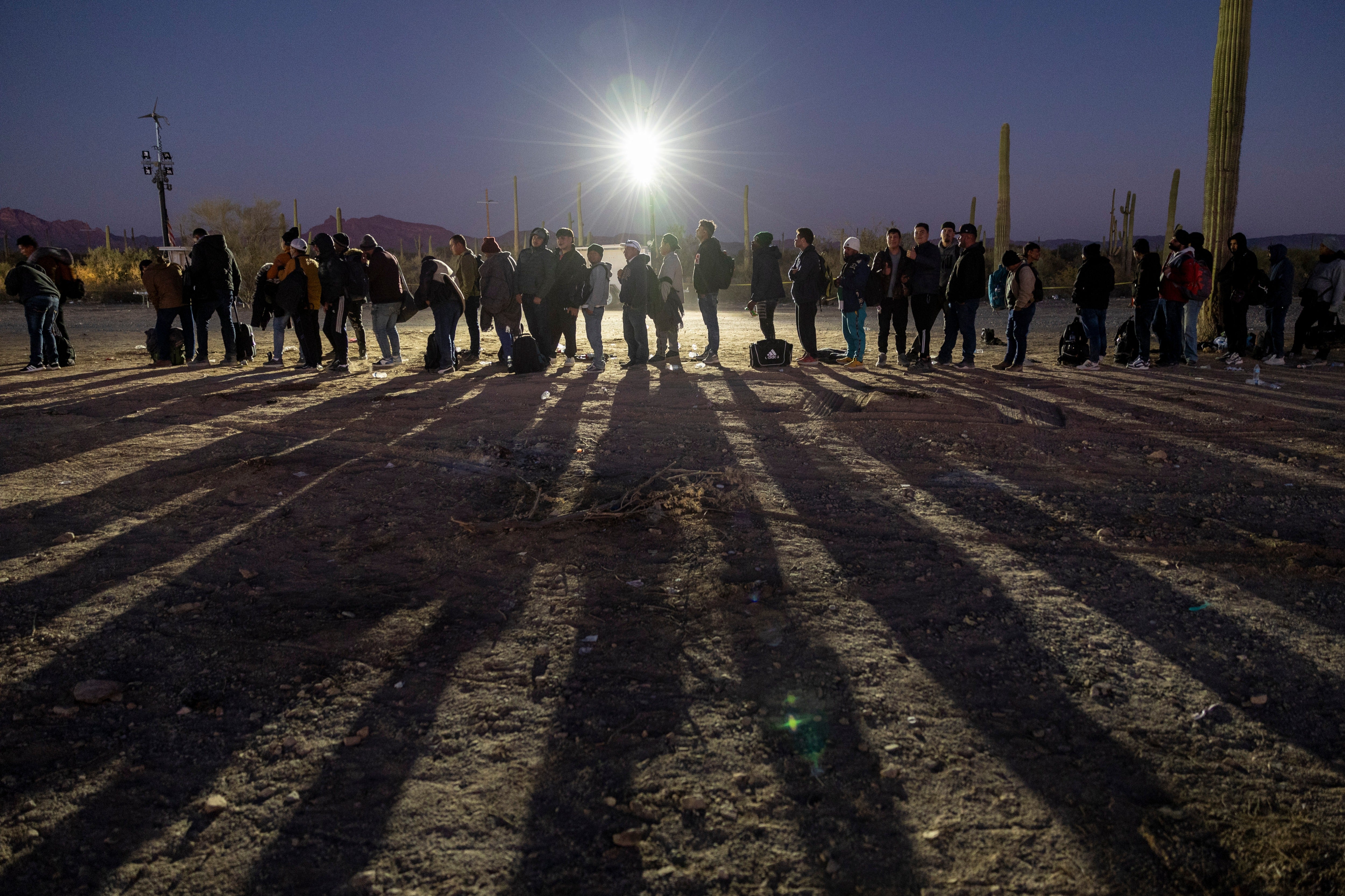 Immigrants line up at a remote U.S. Border Patrol processing center after crossing the U.S.-Mexico border on December 07, 2023 in Lukeville, Arizona