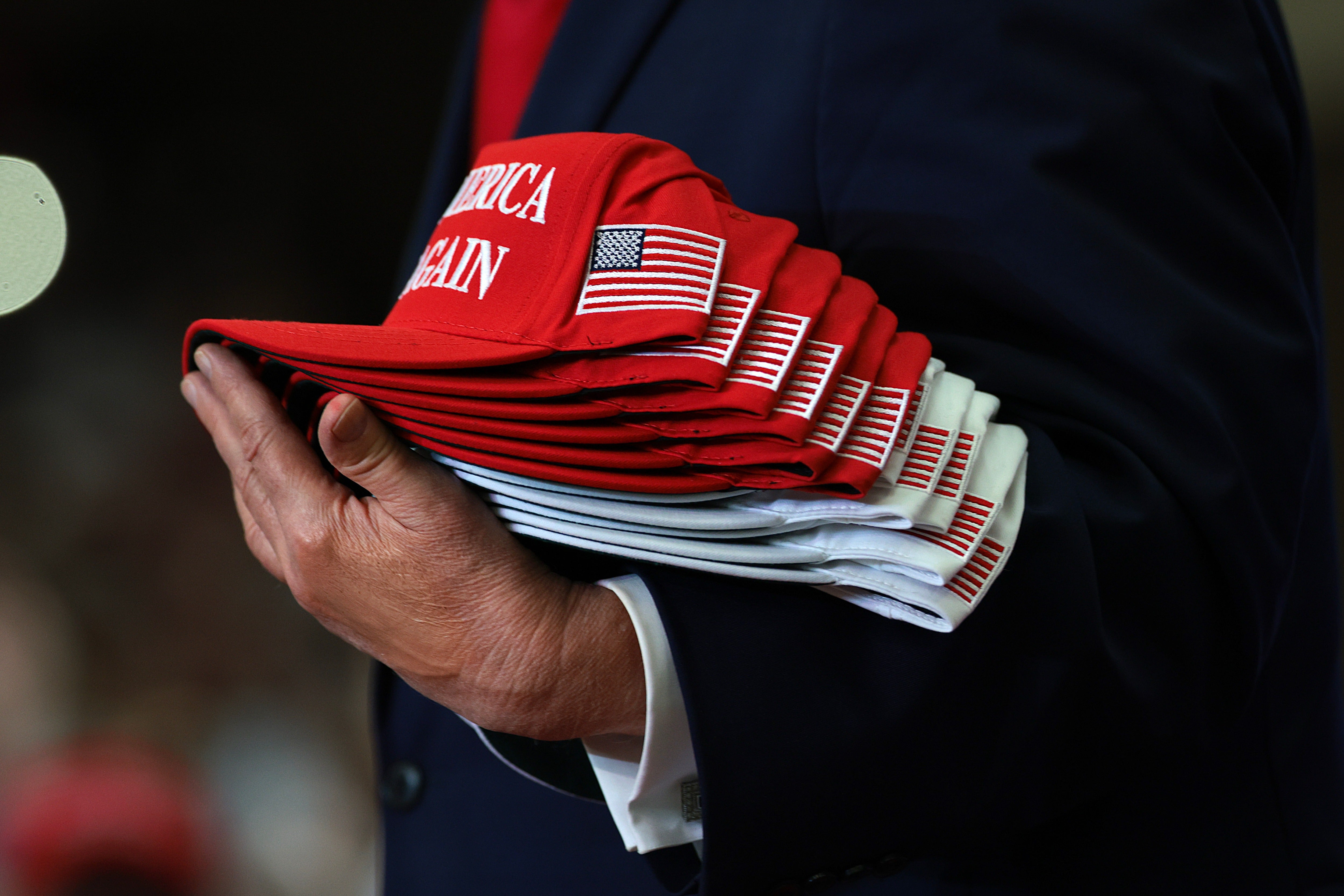 Trump passes out MAGA caps during a campaign rally at Lubbock Memorial Civic Center