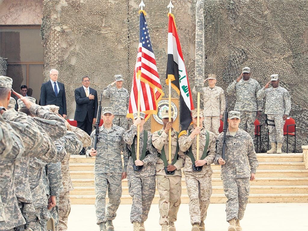 US officials including Defence Secretary Leon Panetta watch the flag-lowering ceremony at a base near Baghdad 