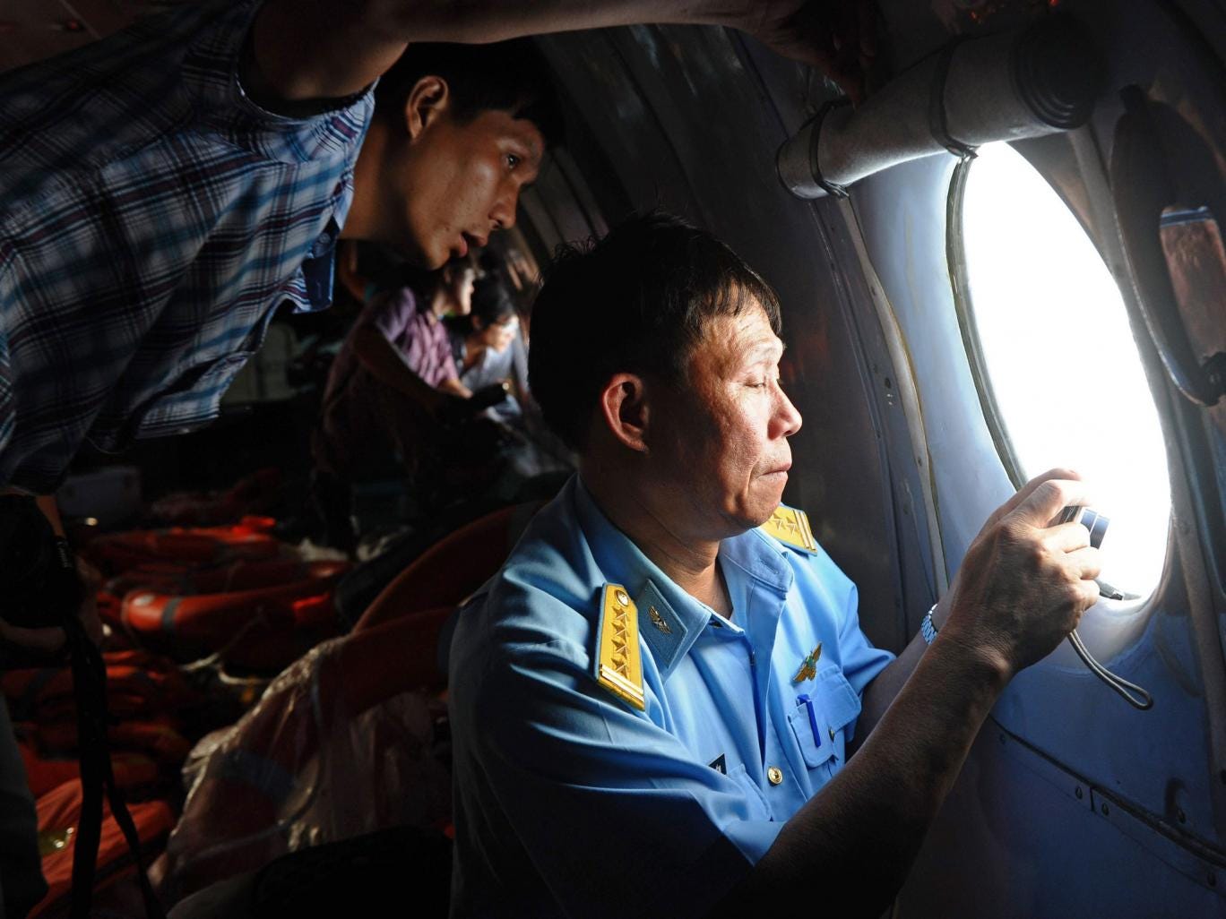 This picture taken from aboard a flying Soviet-made AN-26 used as a search aircraft by Vietnamese Air Force to look for missing Malaysia Airlines flight MH370, shows an officer, right, and a reporter, left, looking out the window during search operations 