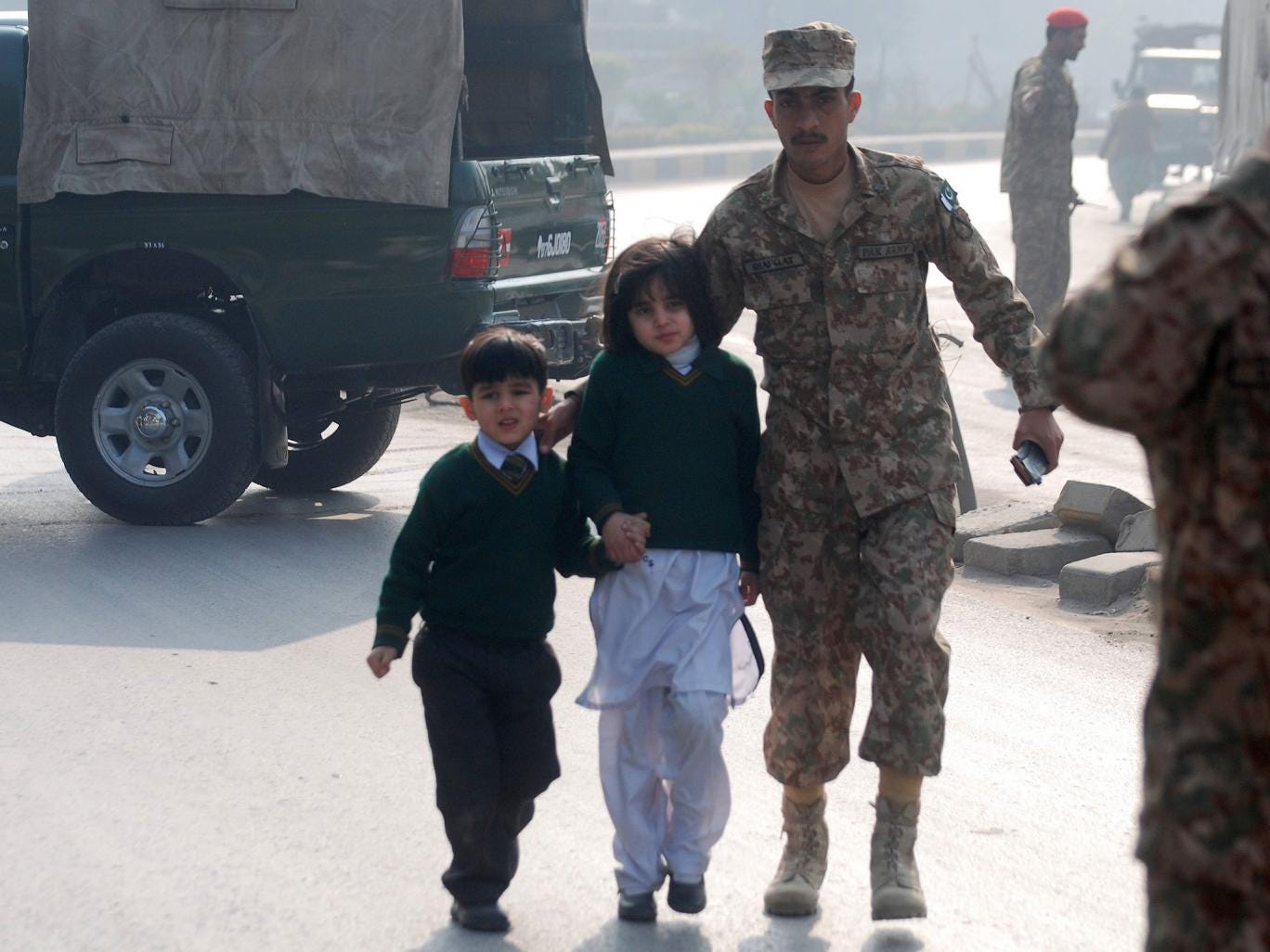 A soldier escorts schoolchildren from the Army Public School that is under attack by Taliban gunmen in Peshawar 