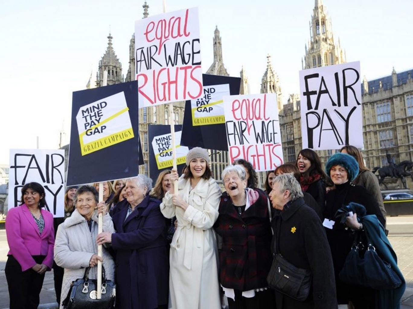 Gemma Arterton (C) holds a placard outside the Houses of Parliament to mark the tabling of the motion on equal pay 