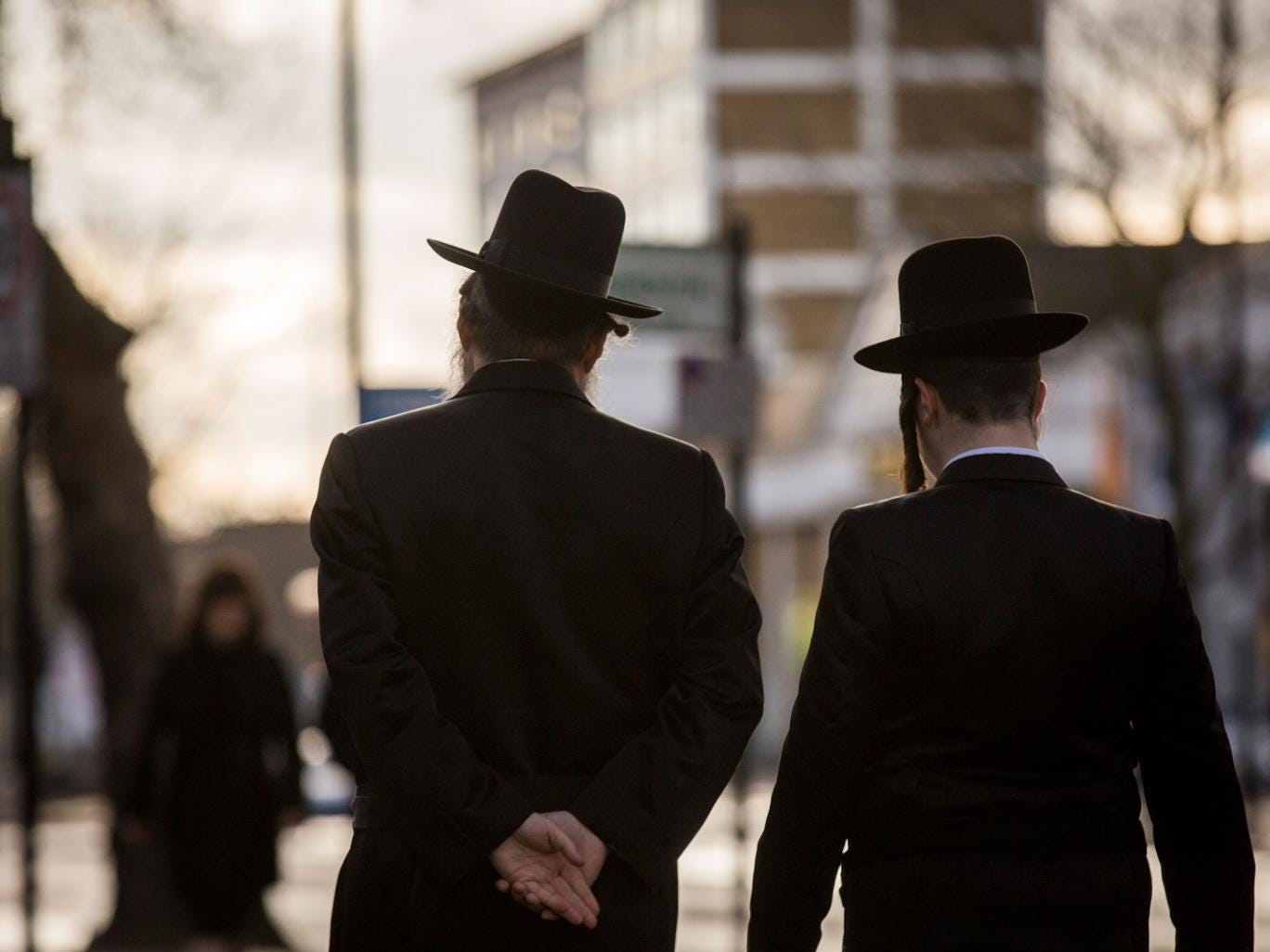 Jewish men walk along the street in Stamford Hill 