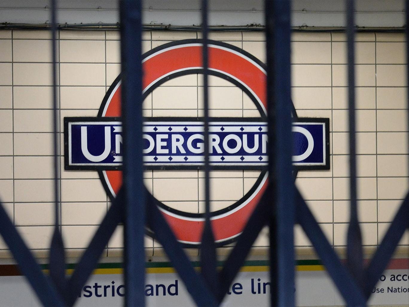 A Underground sign seen through the gates to an entrance at Paddington