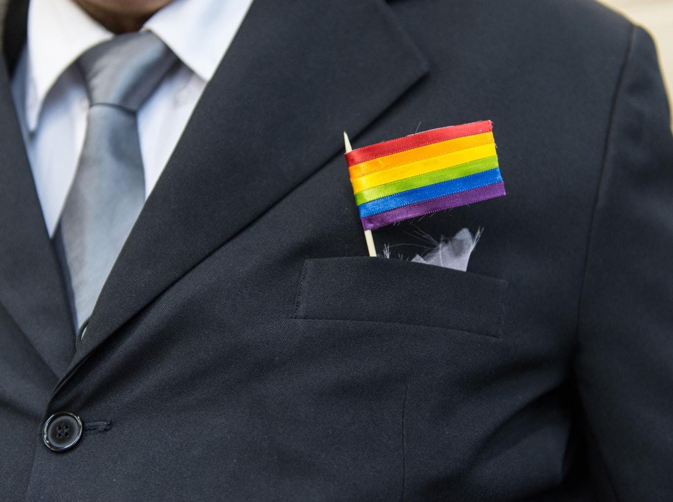 The father of a bride wears a rainbow flag during the wedding ceremony at the Court of Justice of the State of Rio de Janeiro in Rio de Janeiro, Brazil, on December 8, 2013. 130 gay couples are getting married in the first massive wedding ceremony since t