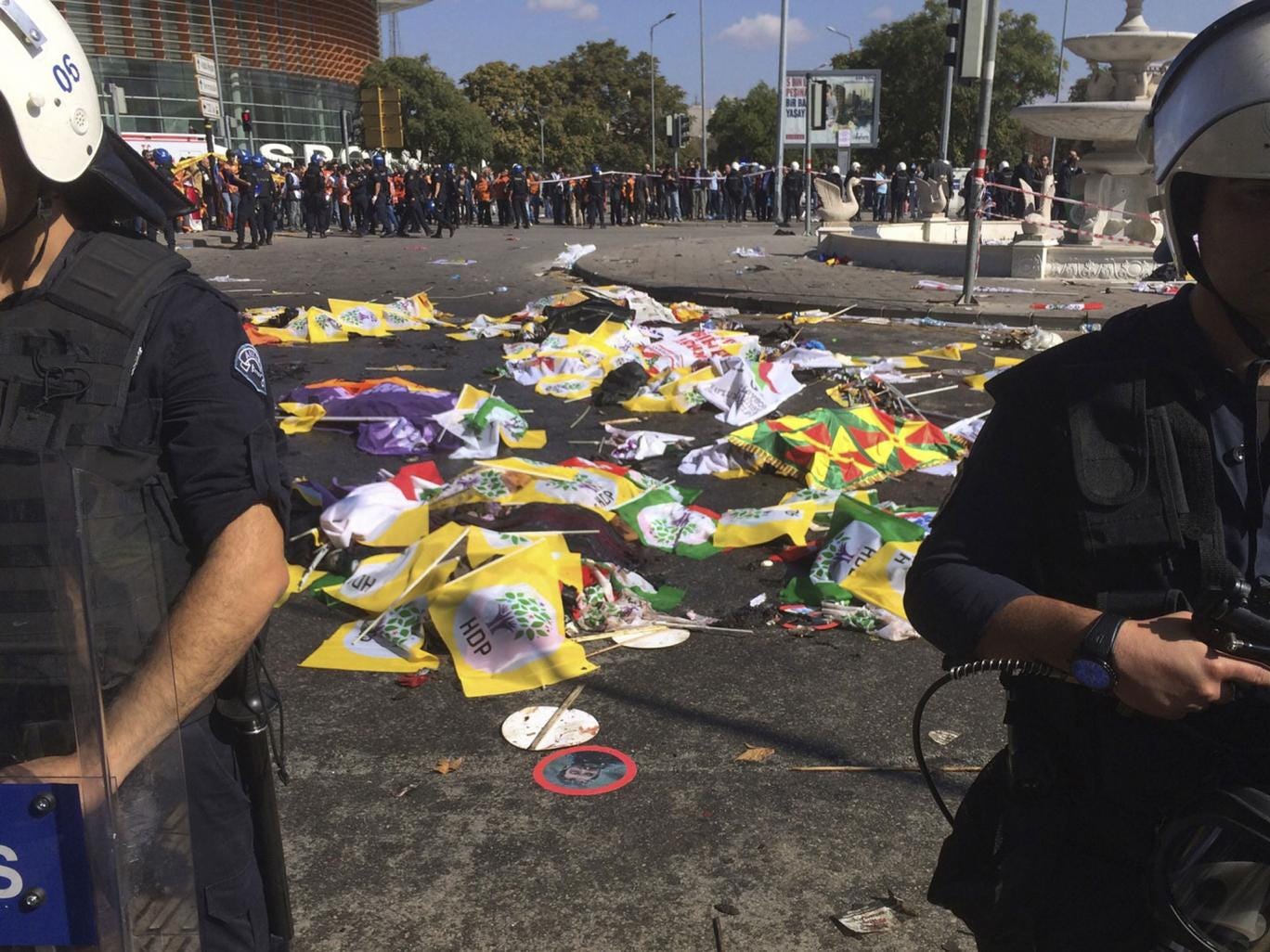Bodies of victims are covered with flags and banners as police officers secure the area after an explosion in Ankara, Turkey, Saturday, Oct. 10, 2015. 