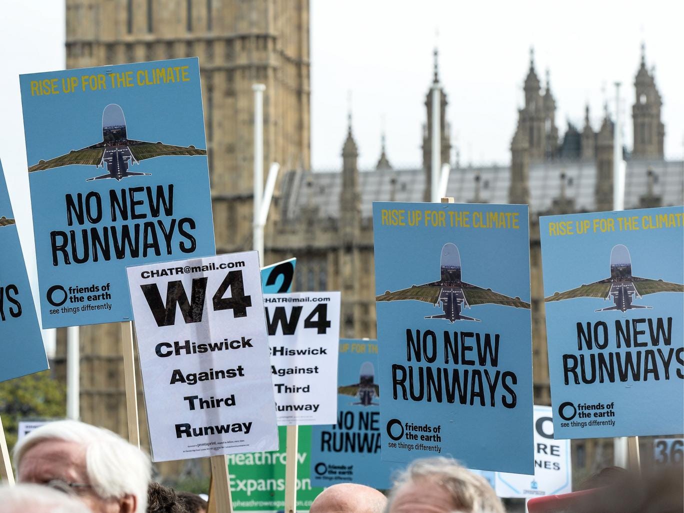Protesters hold signs during a rally against a third runway at Heathrow airport, in Parliament Square
