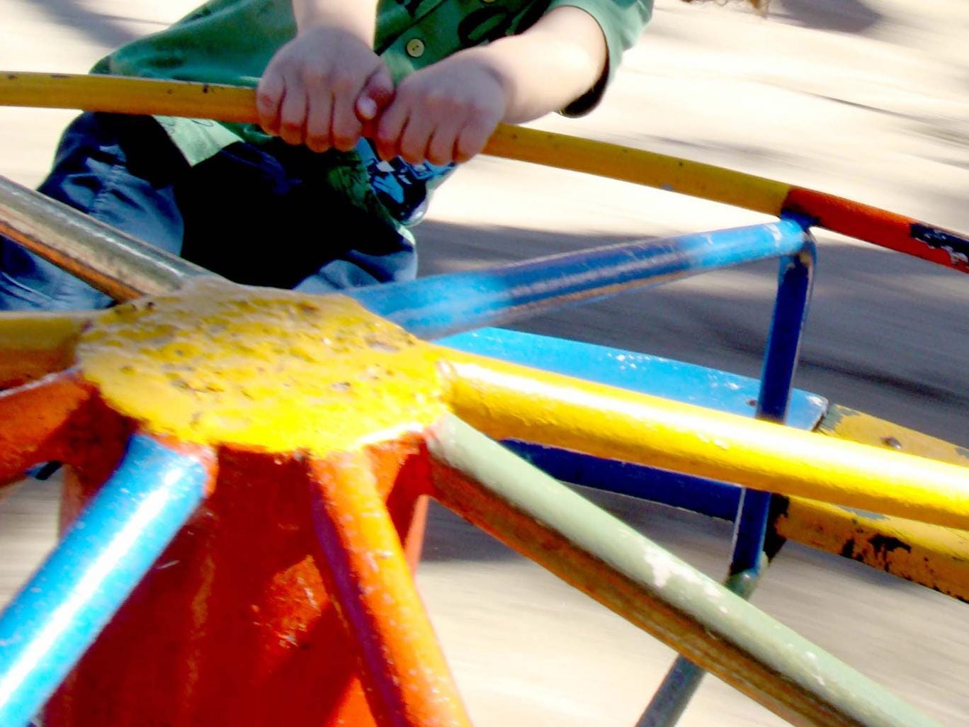 Child playing on a roundabout in the park 
