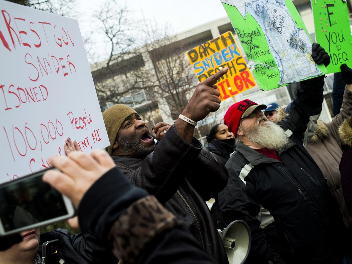 Flint, Michigan residents Arthur Woodson, left, and Tony Palladino Jr. protest the arrival of Flint native and filmmaker Michael Moore as Moore accuses Gov. Rick Snyder of poisoning Flint water during a rally outside of city hall in Flint, Mich. 