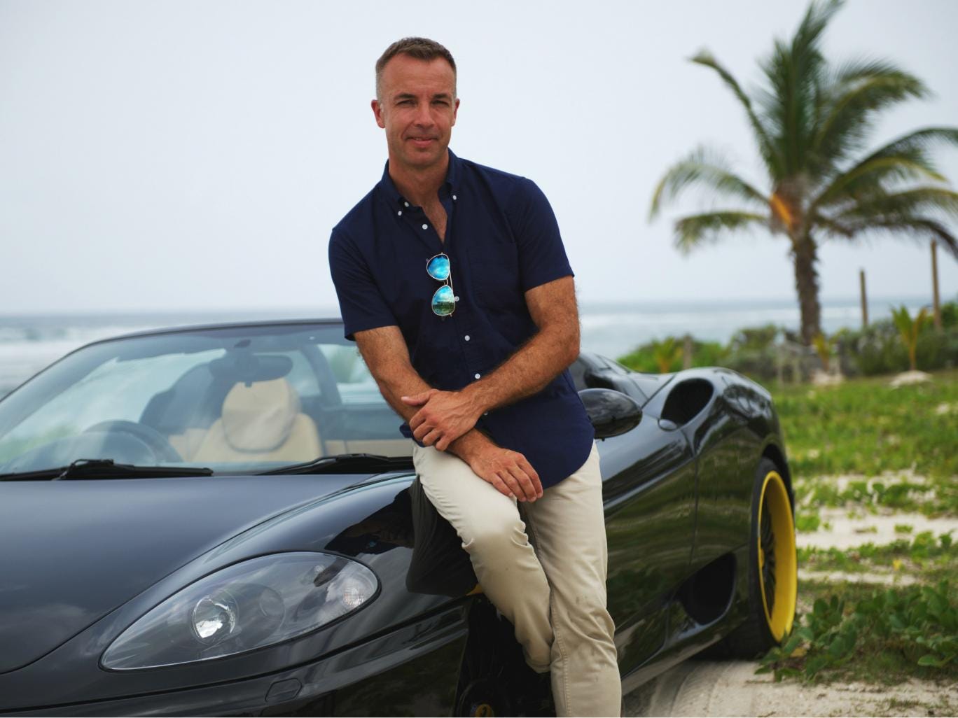 Jacques Peretti stands next to a sports car on the Cayman Islands