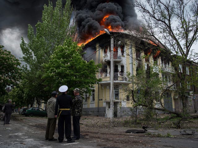 People stand near the burning Mariupol police station 