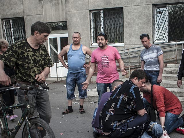 Local residents watch as others give first aid to a man who was shot in the leg by Ukranian militia in the village of Krasnoarmisk. Eyewitness said that Ukranian militia tried to stop the referendum voters briefly taking the City Hall of Krasnoarmisk, where unarmed pro-Russian supporters were gathering. Reportedly the Ukranian militia came out out the building and started shooting at the people, killing at least one man and leaving at least two others injured 