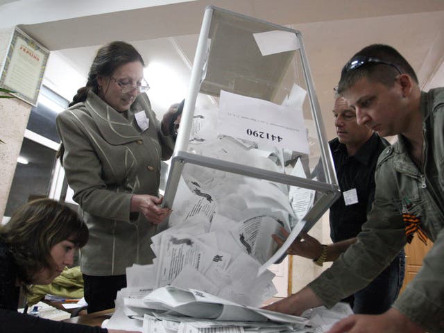 Members of a local election commission empty ballot boxes as they start counting votes after a referendum, at a polling station in Lugansk 