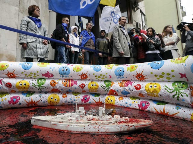 Members of the Democratic Alliance party take part in a performance in front of the French embassy in Kiev. Protesters set up a pool with the blood of animals and models of warships in a protest against French plans for the sale of two Mistral helicopter carriers to the Russian Navy  