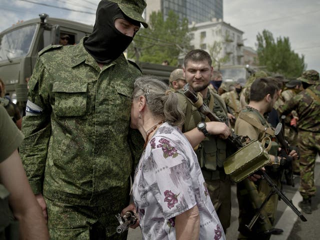 An elderly woman leans against the chest of a pro-Russian gunman in Lenin square in Donetsk 