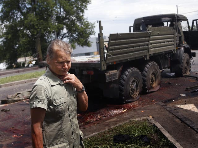 A woman is overcome with emotion as she looks at blood stains and damage around a wrecked truck of supporters of the self-proclaimed 'Donetsk People's Republic' on road leading to the Donetsk International Airport  