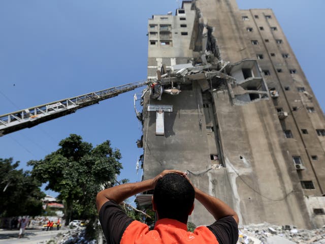 Palestinian rescuers inspect the damage of Al-Shalam (Peace) tower, destroyed by an Israeli strike 