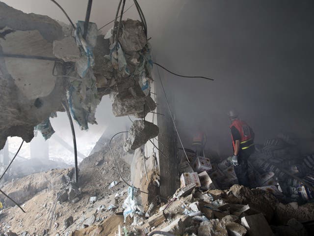 Palestinian firefighters extinguish fire at a house destroyed by an Israeli air strike in Gaza City 