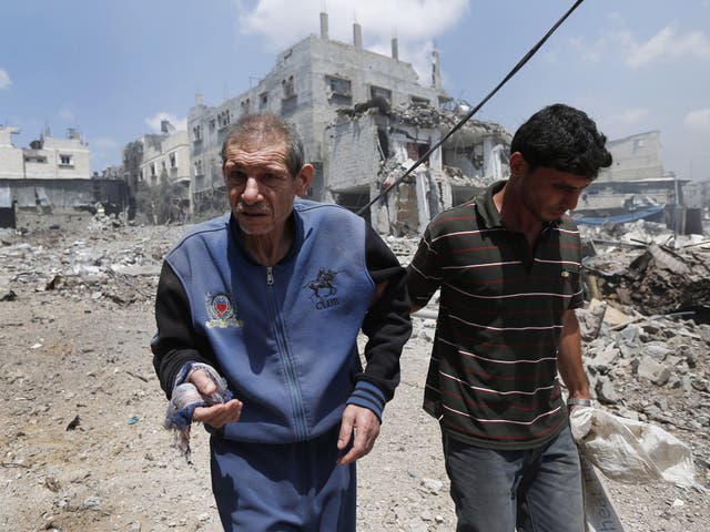 A Palestinian man is helped to flee Gaza City's Shijaiyah neighborhood, after an Israeli strike in the area 