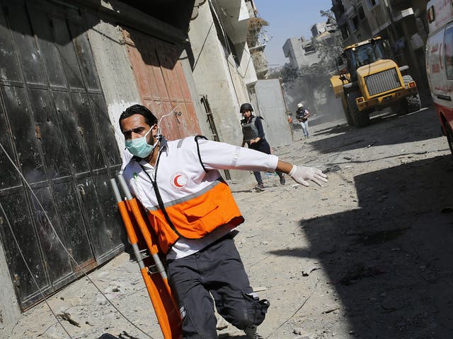 Palestinians paramedics run for cover from Israeli air strike during their search for injured people in the damaged area in Al Shejaeiya neighbourhood, during an Israeli military operation in the east Gaza City 