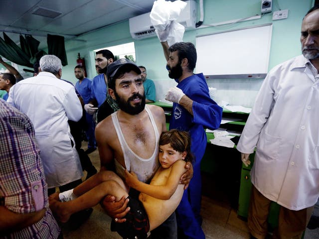 A Palestinian man carries a child, wounded in an Israeli strike on a compound housing a U.N. school in Beit Hanoun, in the northern Gaza Strip, into the emergency room of the Kamal Adwan hospital in Beit Lahiya 