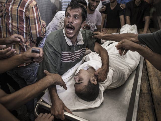 A Palestinian man cries over the body of his son who died when a UN school for refugees was, according to medics, hit by an Israeli tank shell in the Kamal Adwan hospital in Beit Lahiya, Gaza Strip  