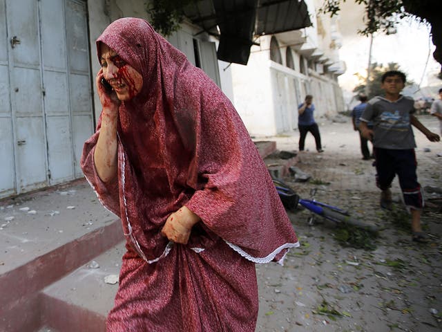 A wounded Palestinian woman runs in the street after Israeli airstrikes in Al Tufah neighbourhood in eastern Gaza City 