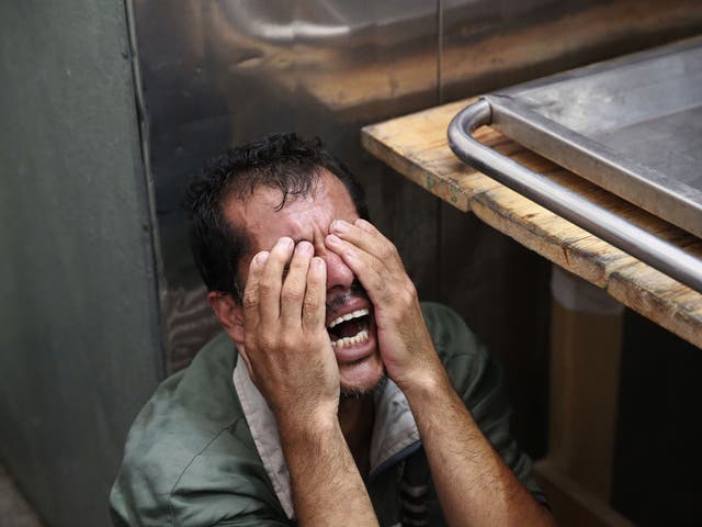 A Palestinian man cries after identifying the body of his loved one, killed in an Israeli strike, inside the morgue of Kamal Adwan hospital in Beit Lahiya, northern Gaza Strip 