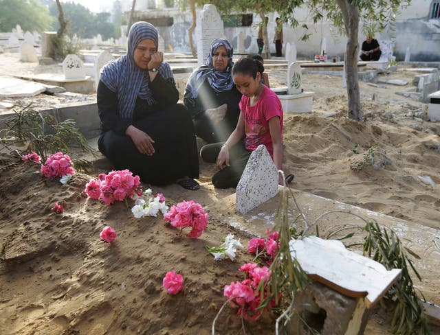 Palestinian Abir Shamaleh, links, sits next to the grave of her son Saher, a civilian according to the family, who was killed in an Israeli strike during the war, as members of the family visit a cemetery in Gaza City. Monday marked the beginning of the three-day Eid al-Fitr holiday, which caps the Muslim fasting month of Ramadan