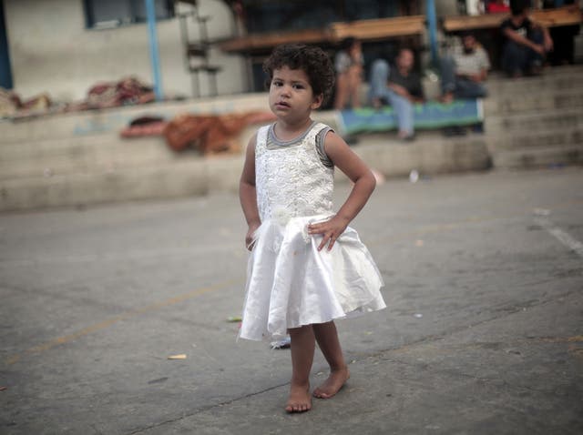 A Palestinian girl poses while playing during the first day of Eid al-Fitr in a United Nations school.Muslims usually start the day by visiting cemeteries, to pay their respects to the dead, and then exchange family visits