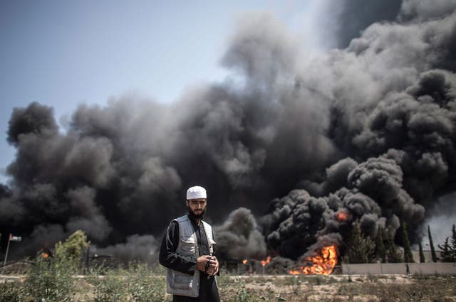 A Palestinian man walks in front of a fire raging at the Gaza's main power plant following an overnight Israeli airstrike, south of Gaza City