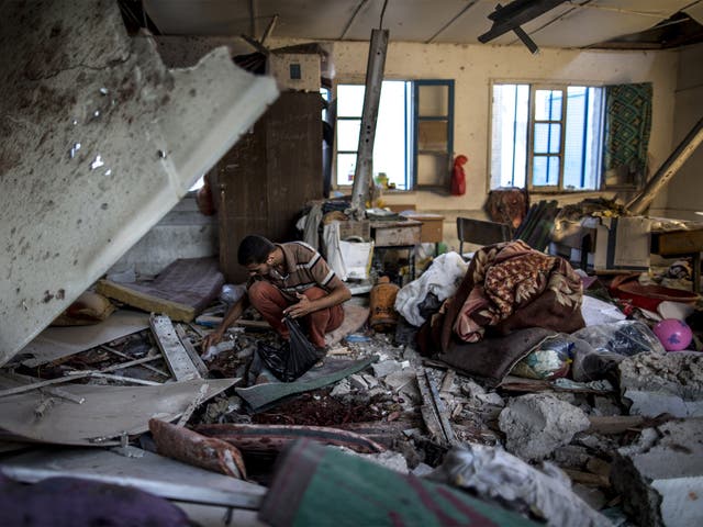 A Palestinian man picks through rubble in a classroom inside a UN school that was hit by shelling
