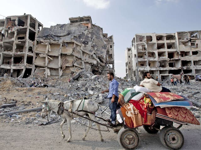 Palestinian men ride a donkey cart past destroyed buildings in the northern Gaza Strip 