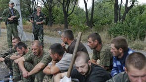 Ukrainian servicemen captured by pro-Russian separatists sit on the ground as they are assigned to clean a street in Snizhne in the Donetsk region