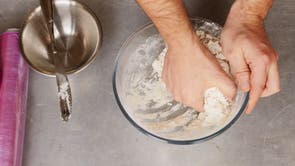 Gradually stir the water into the flour mix, eventually using one hand to pat together into a ball
