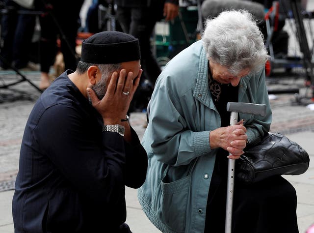 A Jewish woman named Renee Rachel Black and a Muslim man named Sadiq Patel react next to floral tributes in Albert Square