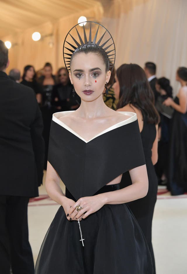 Lily Collins wears a black Givenchy gown and coordinating gothic makeup