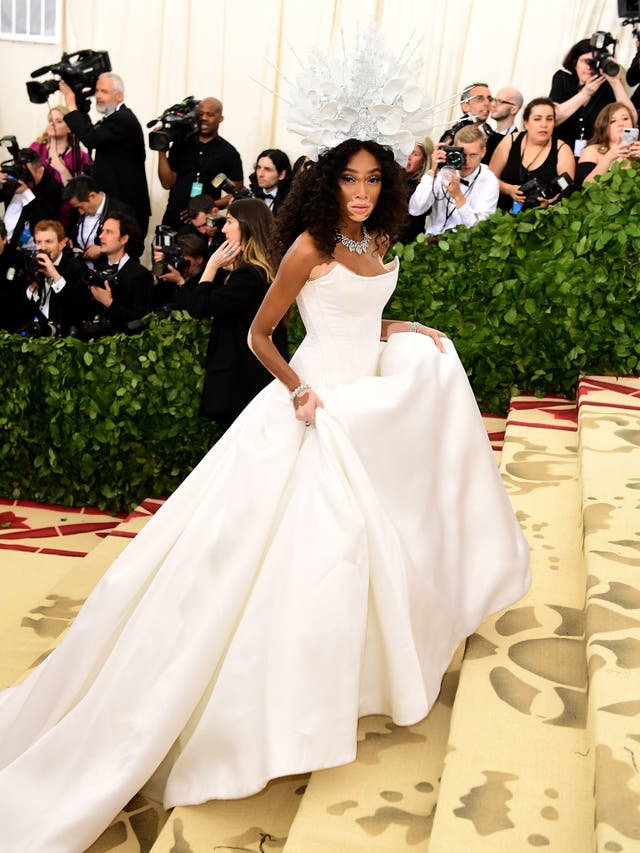 Winnie Harlow wears an all-white Tommy Hilfiger dress with a dramatic train