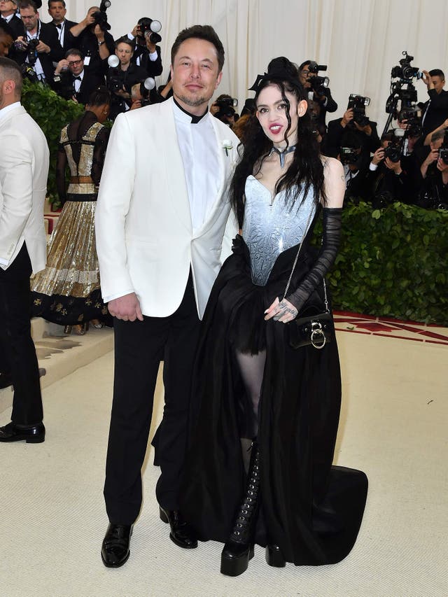 Elon Musk wears a white tuxedo and Tesla pin, while Grimes opted for a black dress and Tesla choker